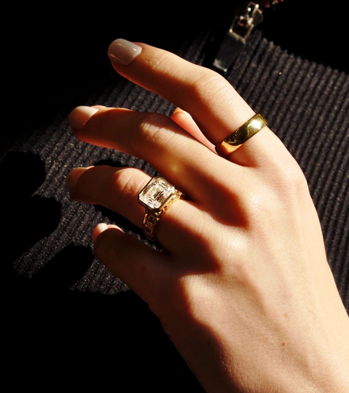 DSC06613-Large | Frank Darling A hang wears two rings: a chunky yellow gold band on their ring finger and a large emerald cut diamond on their pointer finger.