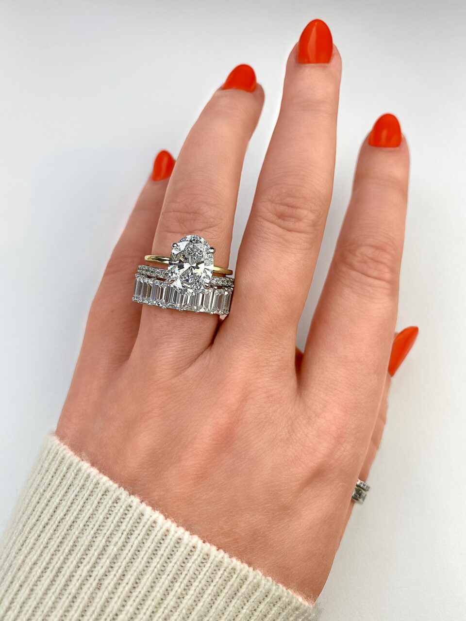 dUJoO-1-dragged_Edited-Large | Frank Darling A large oval solitaire engagement ring rests atop an infinity wedding band that is bedazzled in emerald cut diamonds